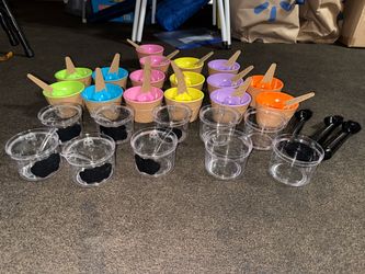 Ice cream cups and spoons in assorted colors . Each cup has matching spoons . 16 cups in total. 9 topping cups with lids and spoon and 3 metal black i