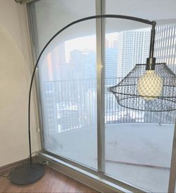black metal arc floor lamp with a wire cage shade