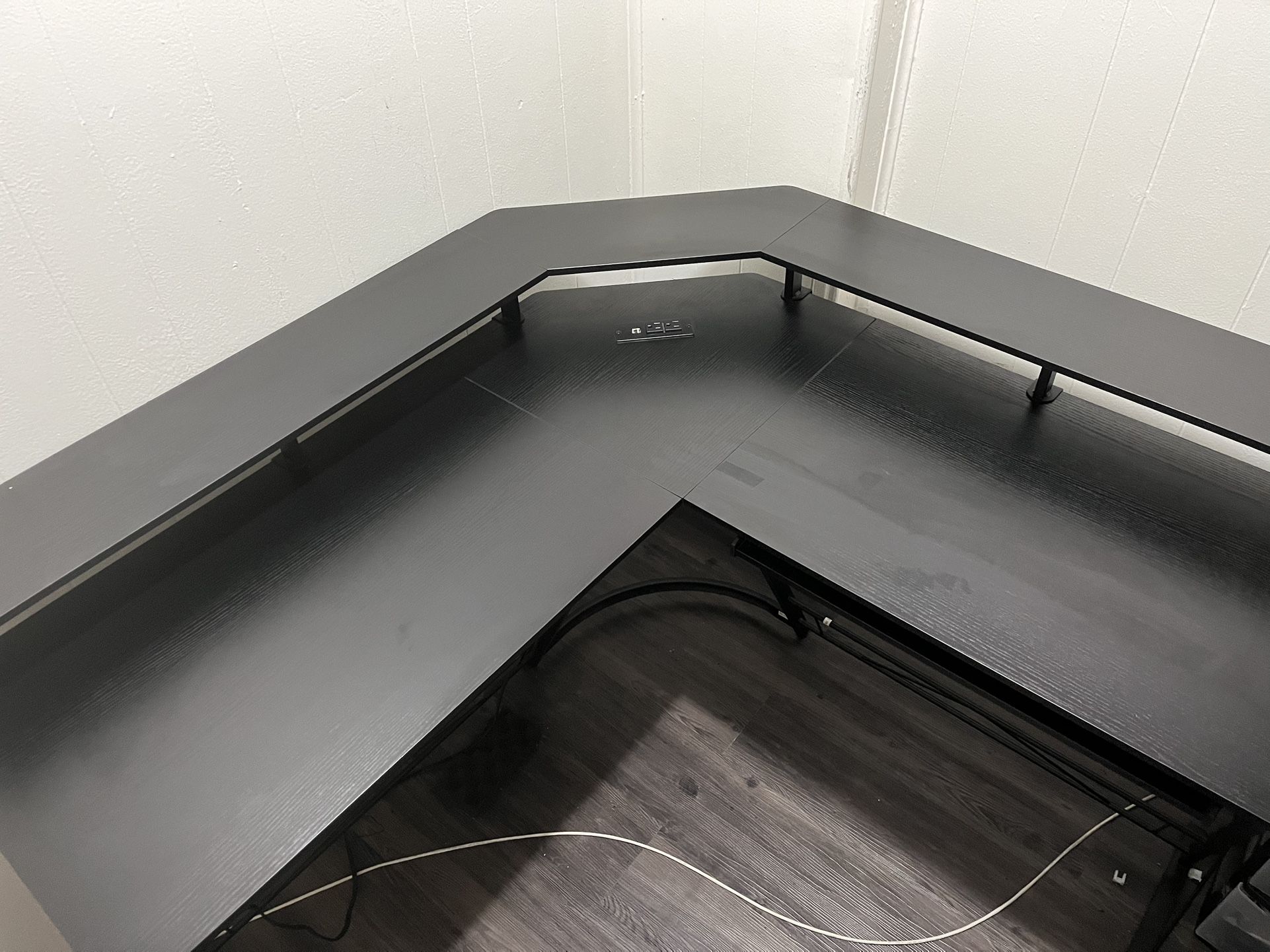 Black wood grain L-shaped table with two outlets and two USB ports for charging a keyboard tray and Desk riser *Price Negotiable*