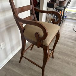 Pair of Regency-style wooden bar stools with scroll arms. Solid wood frames with upholstered seats. Classic elegant design with beautiful curved arm d
