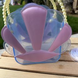 This is a L.O.L. Surprise! Lil Bon Bon clamshell purse with a pearl-style handle