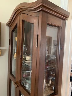 brown wood corner curio cabinet with glass doors and drawers.