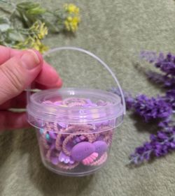 Plastic storage bucket filled with mixed pastel purple for babies hair tied ponytail