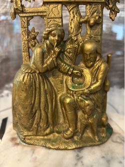 Antique Brass & Marble Girandole Mantle Candleholder featuring a colonial scene of a couple and dog. Available in Coral Gables. 11” (H) x 6” (W) x 4” 