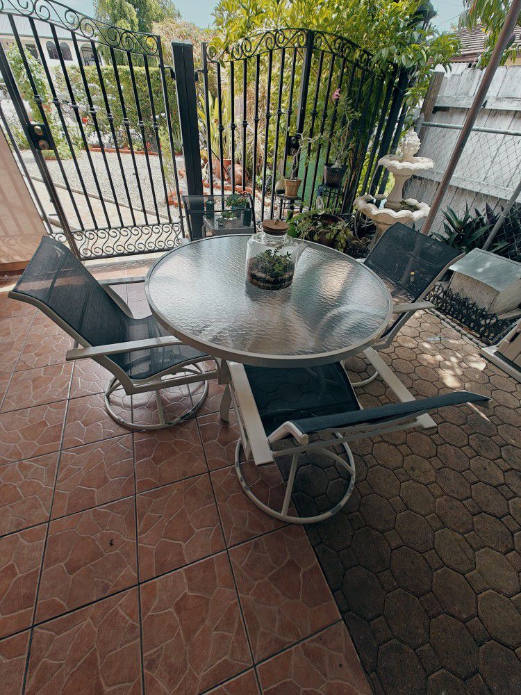 Circular glass-top table and chairs patio set.