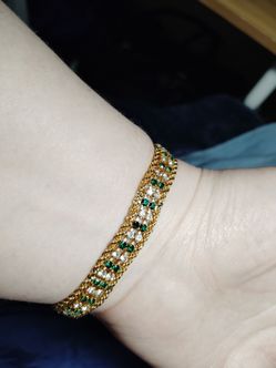 Gold bracelet with green and white gemstones