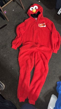 Soft red sherpa fleece onesie with an Elmo character hood. This union suit has a front zipper closure and ribbed cuffs at the wrists and ankles. The m