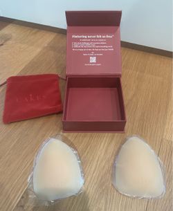 Removable adhesive silicone bra cups in nude tone. Comes with burgundy presentation box and matching pouch. Smooth, triangle shape for seamless wear