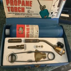 vintage Kmart KM 99 propane torch kit in a blue metal carrying case.Kit ContentsBlue propane cylinderBrass valve torch handleInterchangeable burner he