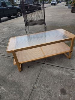 Rattan coffee table with two tiers and a glass top, modern style.