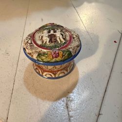 This is a vintage porcelain trinket box, possibly of German origin, featuring a raised design with figures and floral motifs.