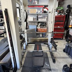Squat Rack, Adjustable Bench, Plates, And Curl Bar. 