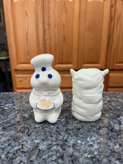 Ceramic Pillsbury Dough Boy and Flour Sack Pair of Salt and Pepper Shakers.  Year 1997.  Brand new never used.  Have been on display in a cabinet with