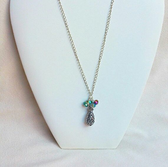 Necklace with carved hollow teardrop pendant in antique silver color and small faceted beads on a silver colored chain