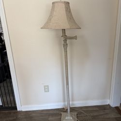 Farmhouse vintage-style floor lamp features an antique white metal stem