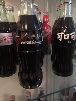 Coke collection in glass show cases. Old numbered bottles, xmas, olympics, foreign, extensive collection with some memorabilia included