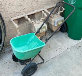 Scotts Turf Builder EdgeGuard Mini broadcast spreader, identifiable by its distinct bright green hopper and black handle.