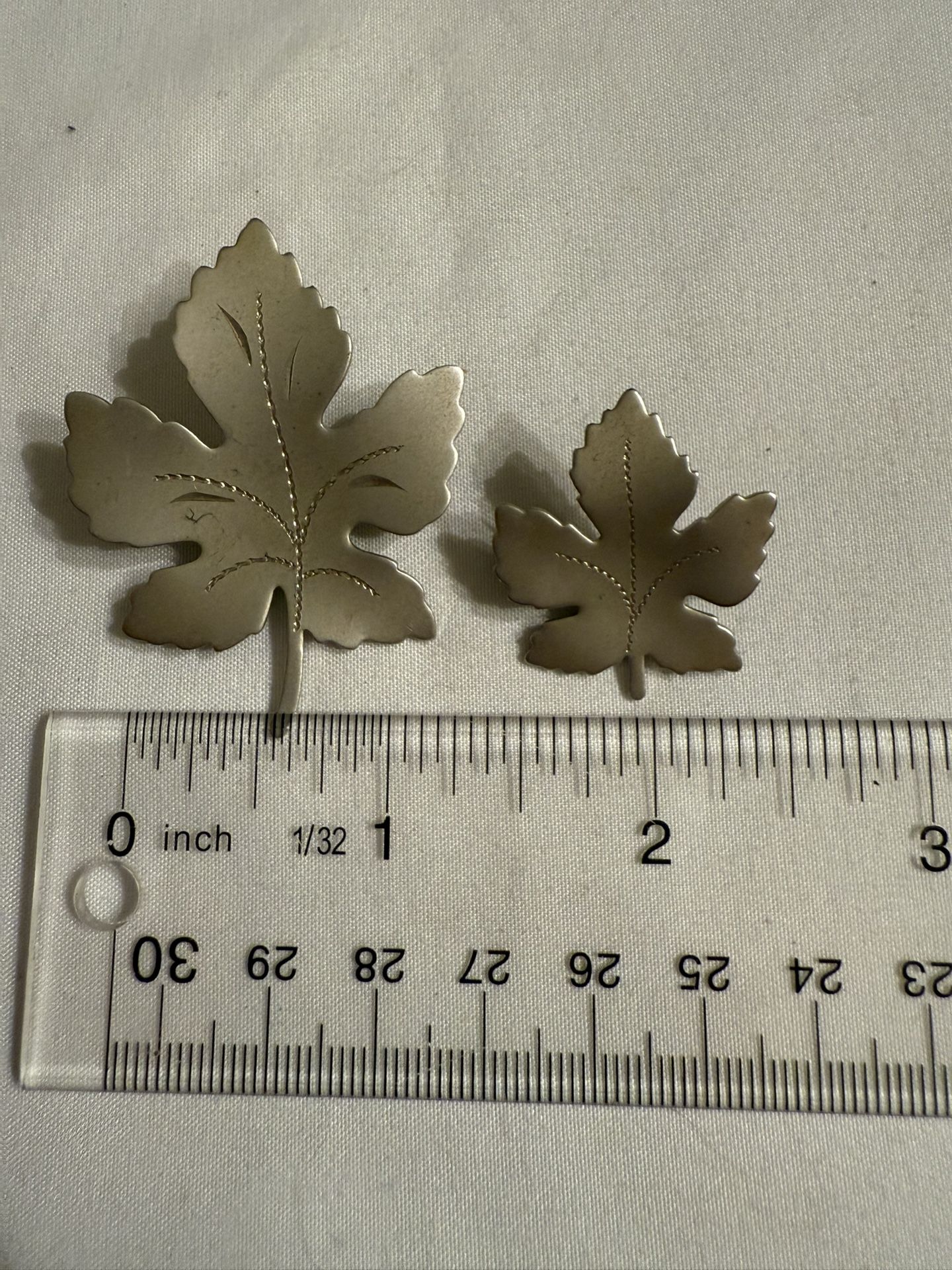 Two two vintage-style maple leaf brooches made of a silver-toned metal