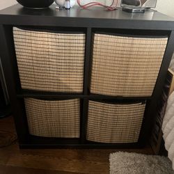 IKEA Black shelf with four woven baskets .