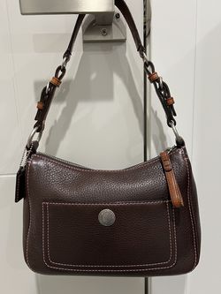 Classic Coach bag. Dark brown pebbled leather with cool pink stitching. Has a front pocket and a zip top closure. Inside is a pretty pink lining with