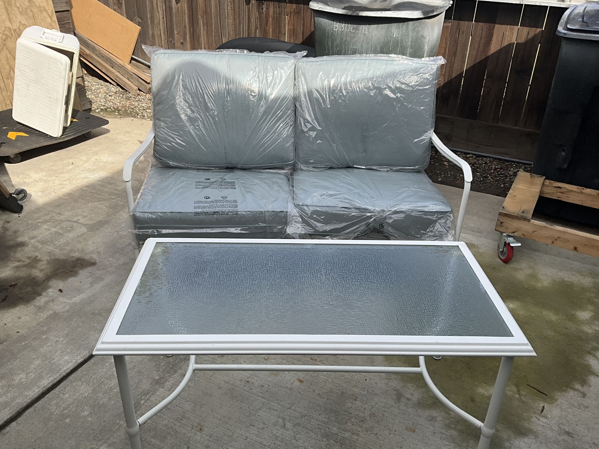 NEW OUTDOOR LOVESEAT AND TABLE WITH GLASS TOP IN WHITE WITH CUSHIONS