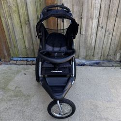 Baby Trend Expedition Jogger stroller. The stroller is a three-wheeled jogging stroller with a large canopy and a storage basket underneath. The front