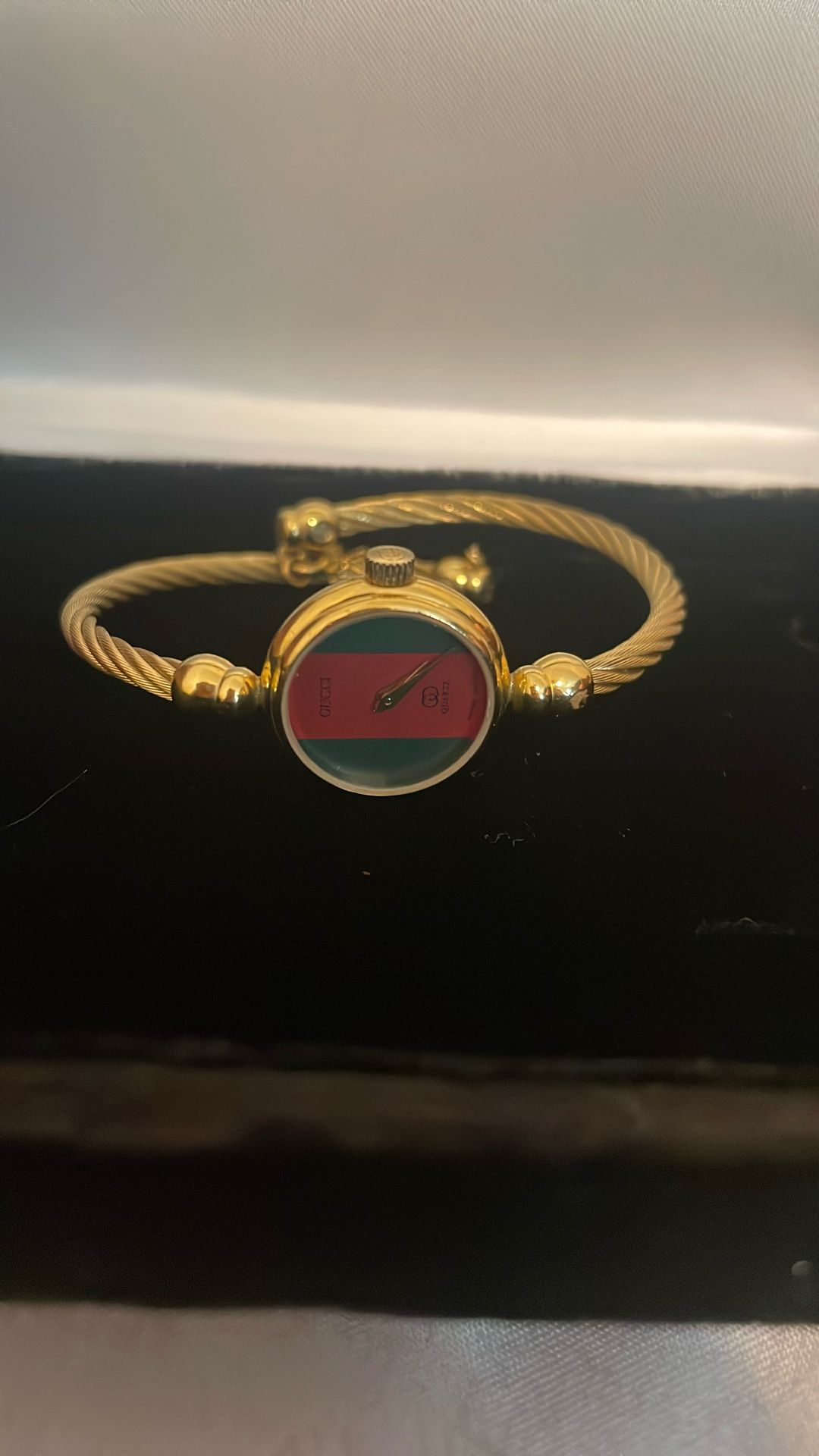 Vintage Stylish Gucci 2047 Swiss made bangle watch featuring a gold bracelet and bold red and green dial.