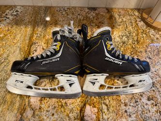 Pair of black and yellow Bauer Supreme ice hockey skates equipped with Tuuk Lightspeed Pro holders