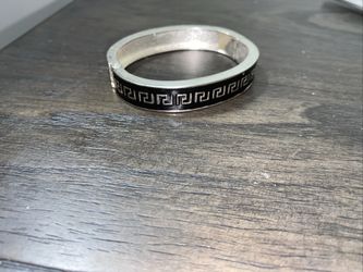 This is a sterling silver hinged bangle bracelet with a black Greek key pattern. 