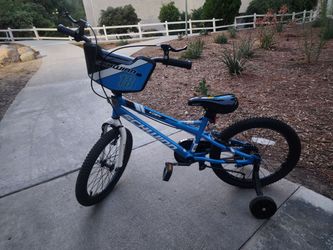 This blue and black Schwinn Koen 18-inch bike features a BMX-style frame and includes training wheels for beginners