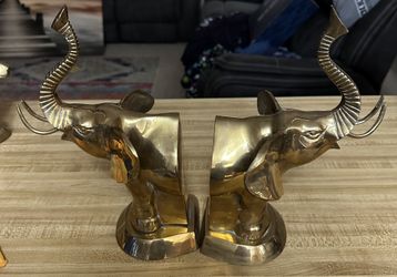  is a vintage solid brass elephant bookend with its trunk up.