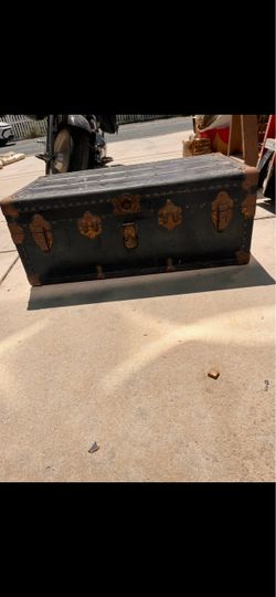 This is a vintage early 20th-century metal covered flat-top steamer trunk.