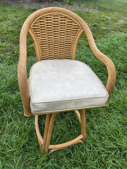rattan swivel bar stool with a cushioned seat.