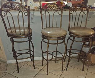 These are wrought iron or metal scroll-back swivel bar stools with upholstered seats