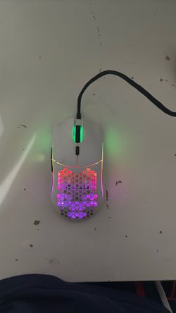 White gaming mouse with honeycomb design. It has RGB lighting and is wired. Glorious Model O.