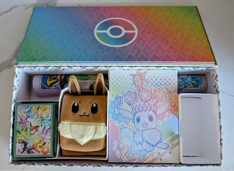Pokémon Prismatic Evolutions Box, an Eevee Deck Box, Playmat Featuring Eevee and Evolutions, and Sleeves