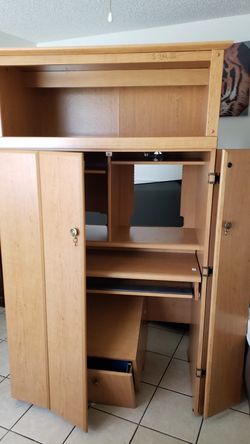 Big computer desk with file cabinet and light.
