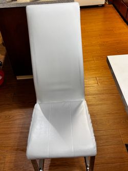 A set of four white leather dining chairs;