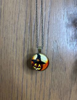 Necklace with a pendant that has a jack-o-lantern wearing a witches hat