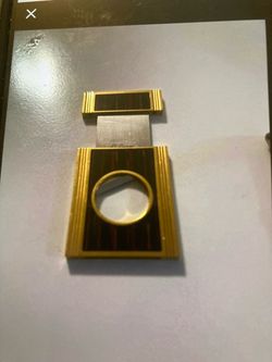 n S.T. Dupont Cigar Cutter and Stand, specifically finished in gold and a rich brown wood-tone or lacquer design.Dual Functionality: This luxury acces