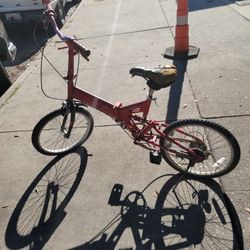 This is a red full-suspension folding bicycle. 