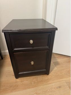 Dark brown Two-drawer filing cabinet with wheels.  Height = 24 inches Width = 17 1/2  Depth = 22 inches
