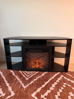 Small wooden TV stand with fire place and space heater.