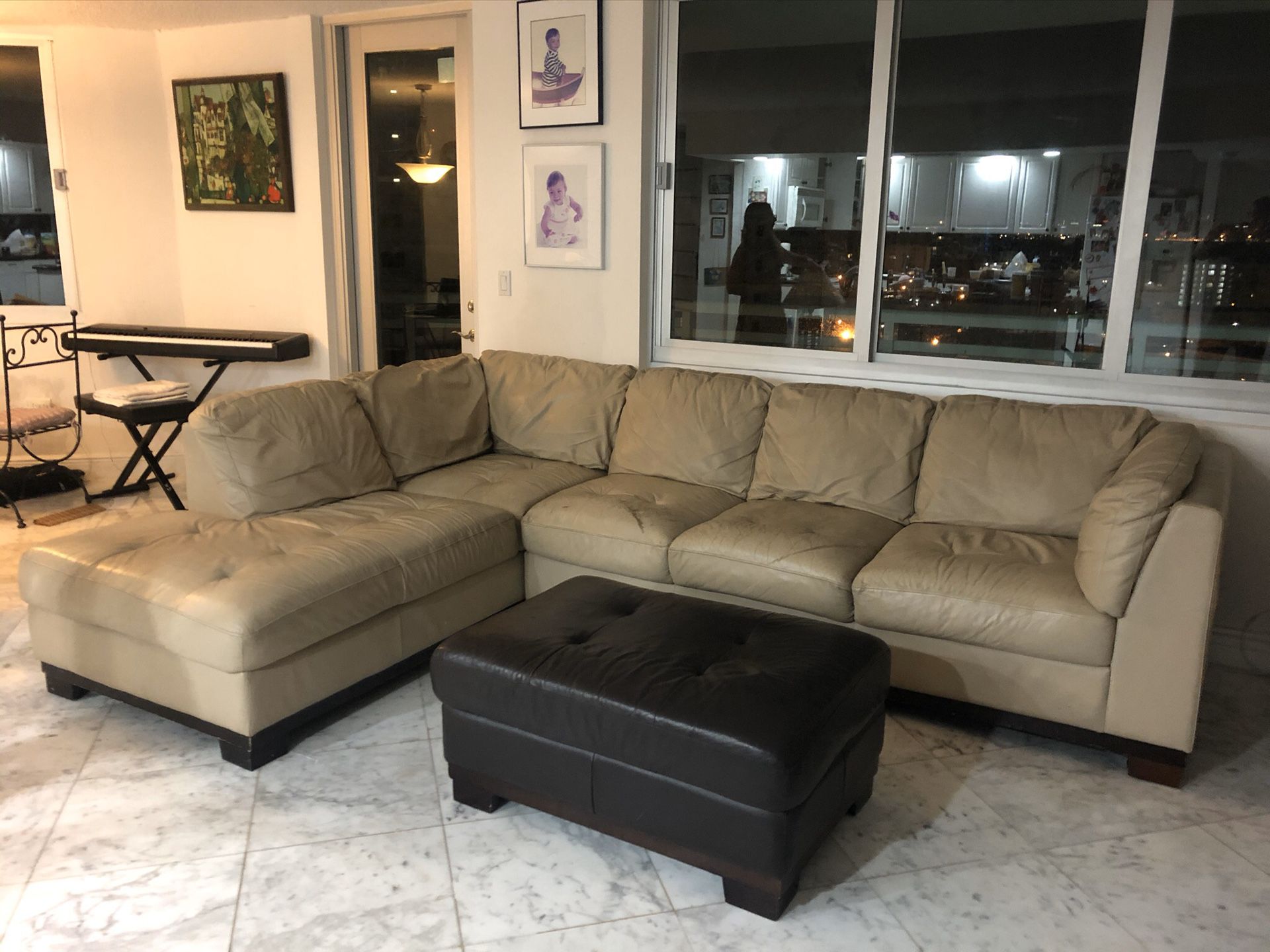 Beige sectional leather couch with brown ottoman.