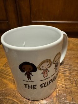 Ceramic mug features chibi-style illustrations of notable political figures labeled "The Supremes