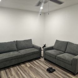 2 gray sofas and a square dining table with 4 chairs