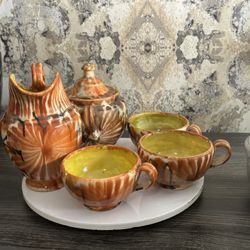 decorative ceramic tea set, likely vintage, featuring a distinctive orange and brown glazed pattern with yellow interior glaze on the cups.