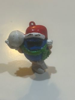 vintage blue peanut M&M Christmas ornament wearing a Santa hat, sunglasses, and a green scarf while holding a snow or candy prop. It resembles holiday