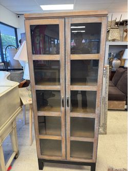 Curio cabinet features a rustic, distressed warm pecan brown finish with a black base - 28” x 16” x 70