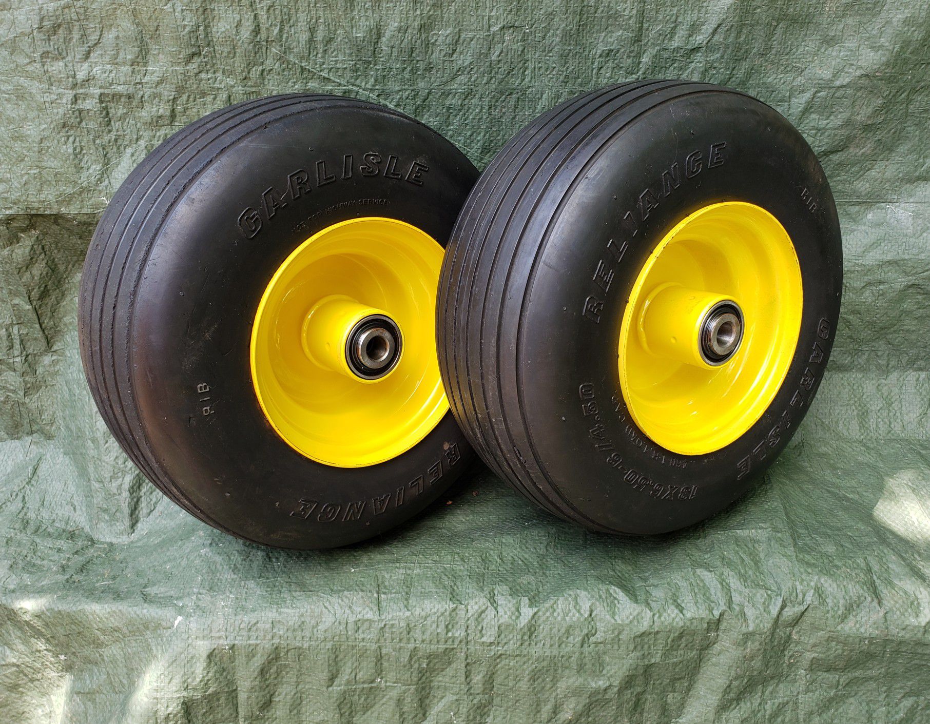 Pair of 13x6.50-6 Reliance Flat Free ribbed lawnmower tires on JD yellow wheels for zero turn mowers